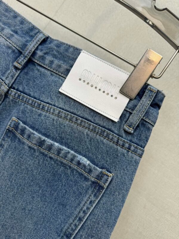 Miu Miu style jeans with rhinestone embellishments on the cuffs, made with high-quality fabric and a special washing process.